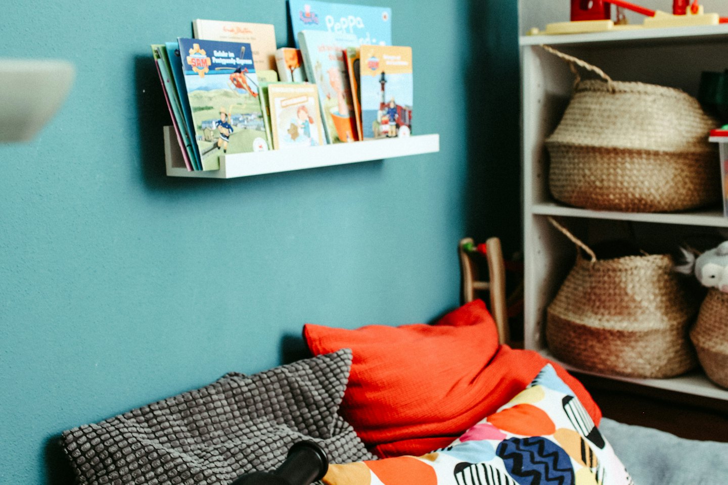 Colorful books on shelves above pillows in a reading nook.