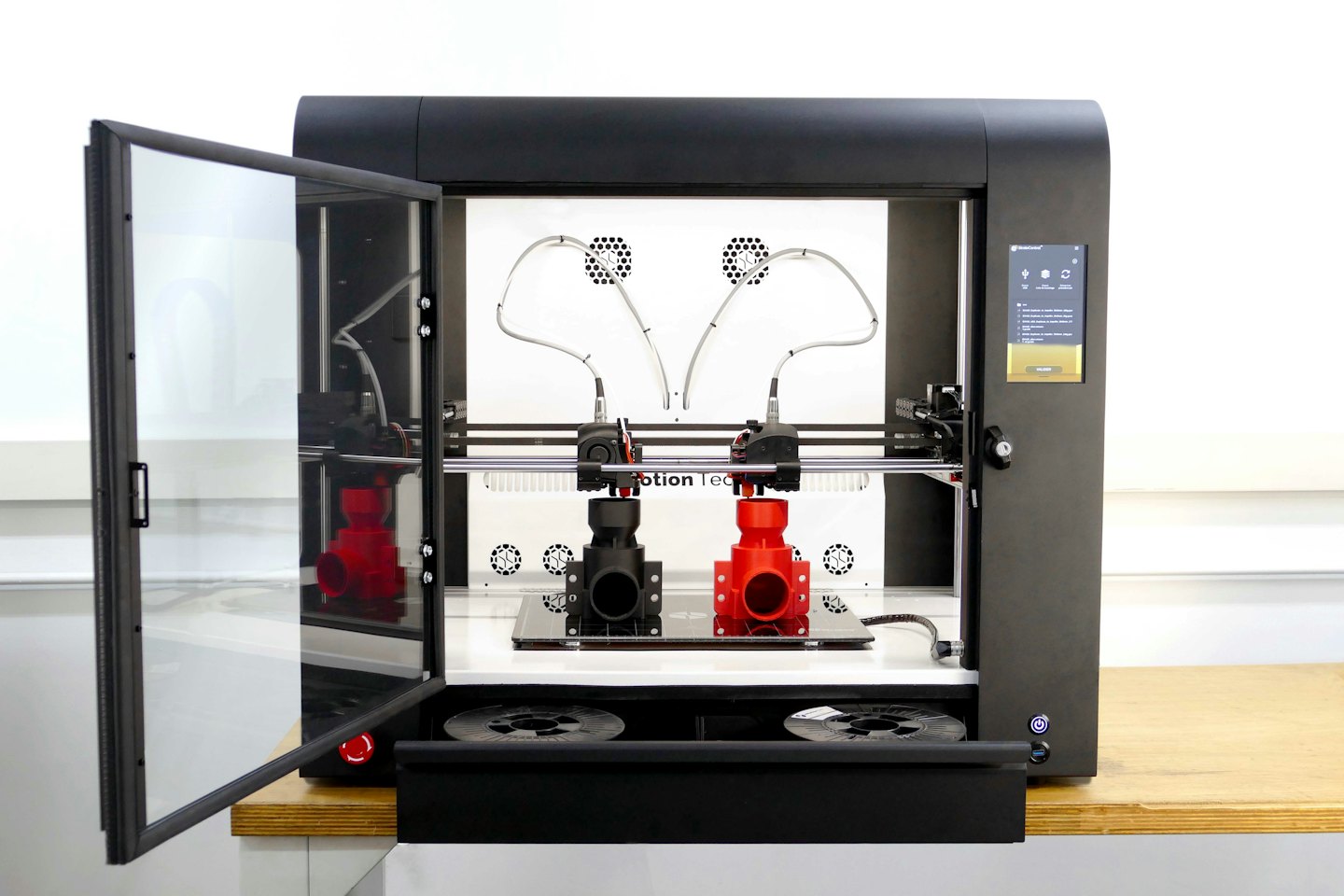 Black industrial 3D printer with door ajar in workshop.