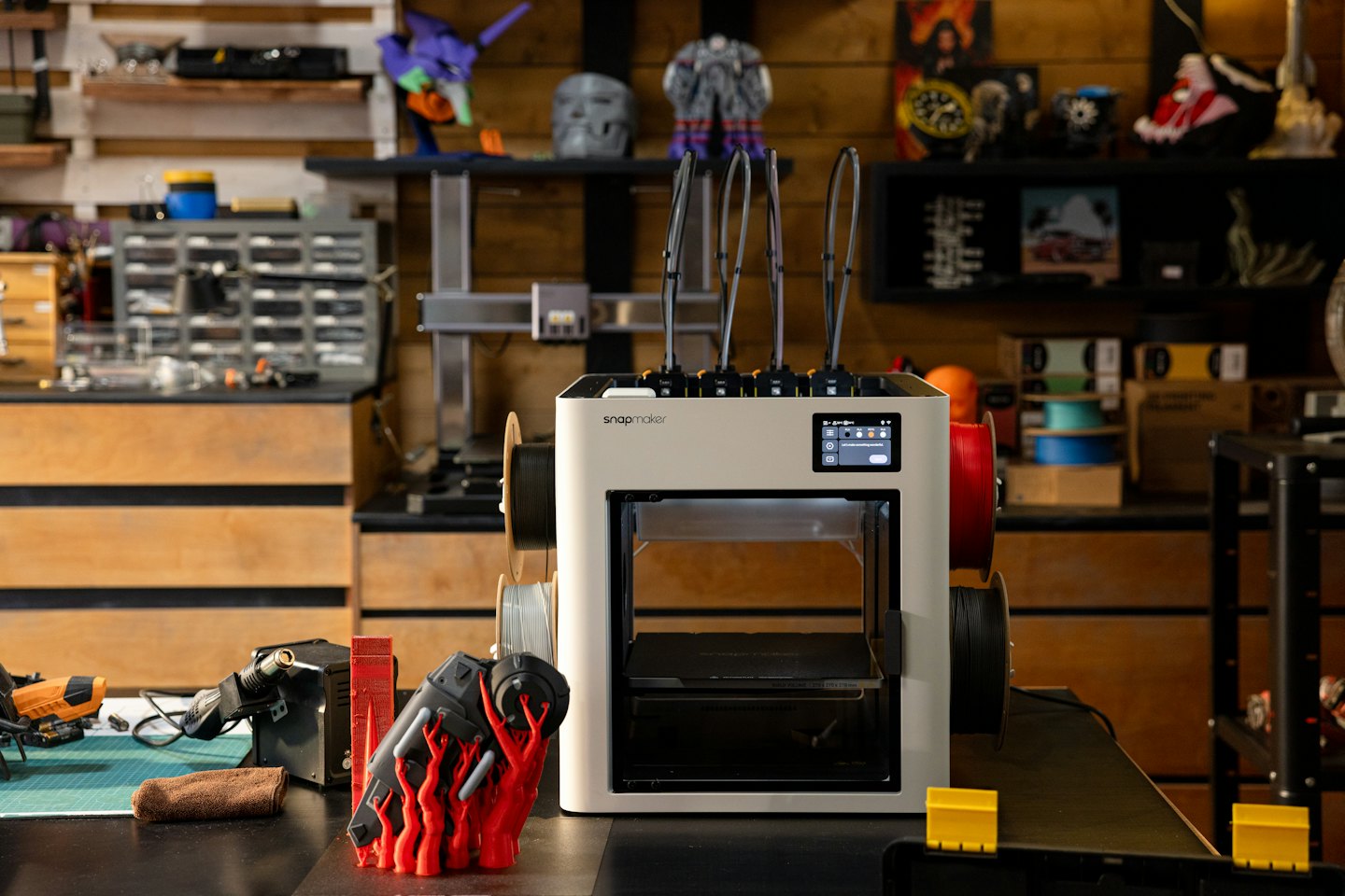 Snapmaker 3D printer on a workbench with tools and supplies.
