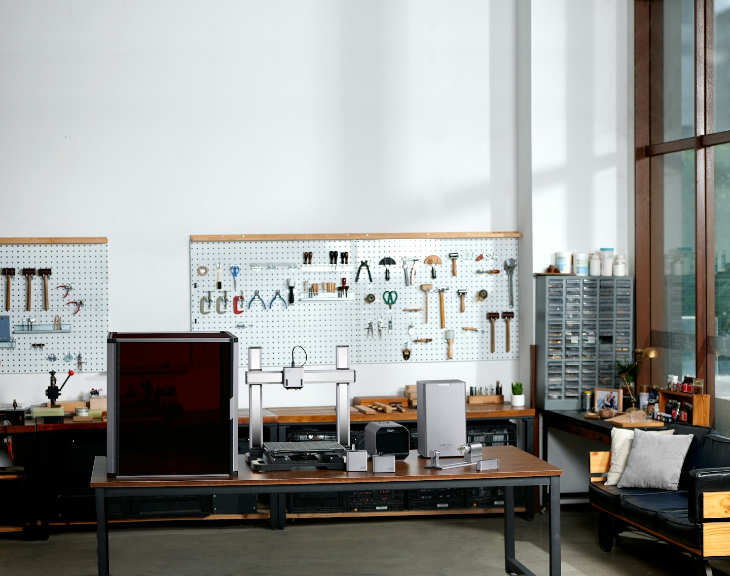 Modern maker space with 3D printer and tools on table.